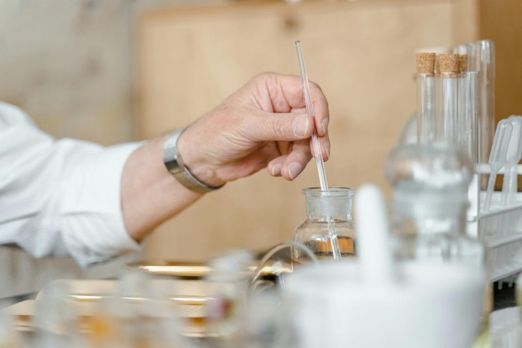 Close-up of a person mixing chemicals in a laboratory with glassware.
